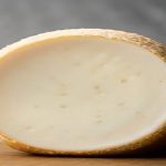 Demi-meule de fromage à pâte pressée sur une planche de bois, fond de cave